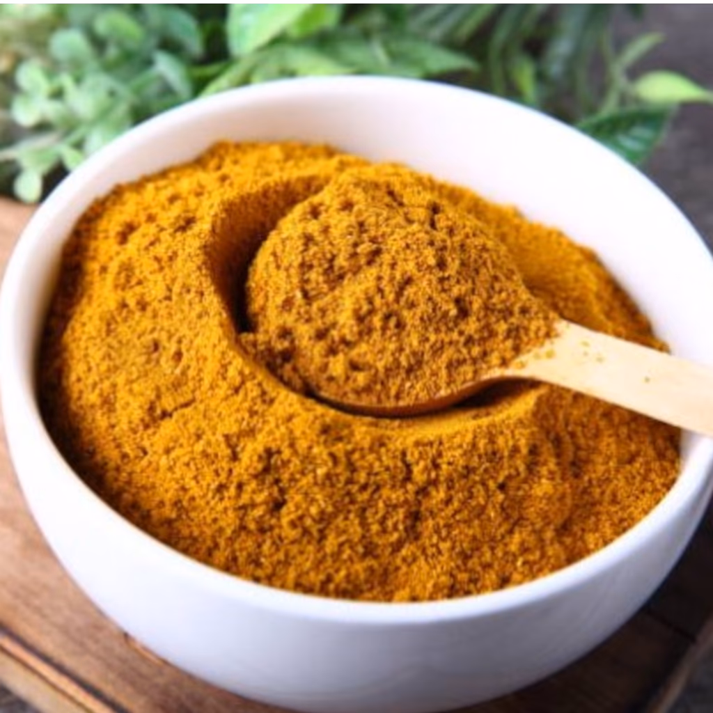 Petit bol de Garam Masala maison réalisé au Thermomix TM5 TM6 avec poudre d'épices brun doré entourée de graines de coriandre, cannelle, cardamome et clous de girofle.